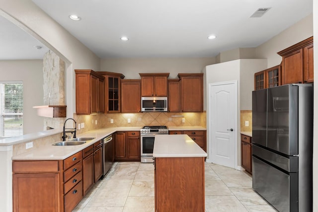 kitchen featuring light countertops, a sink, a center island, stainless steel appliances, and decorative backsplash