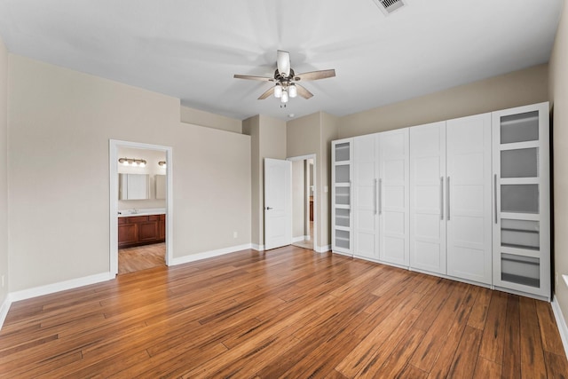 unfurnished bedroom with hardwood / wood-style floors, ensuite bathroom, baseboards, and visible vents