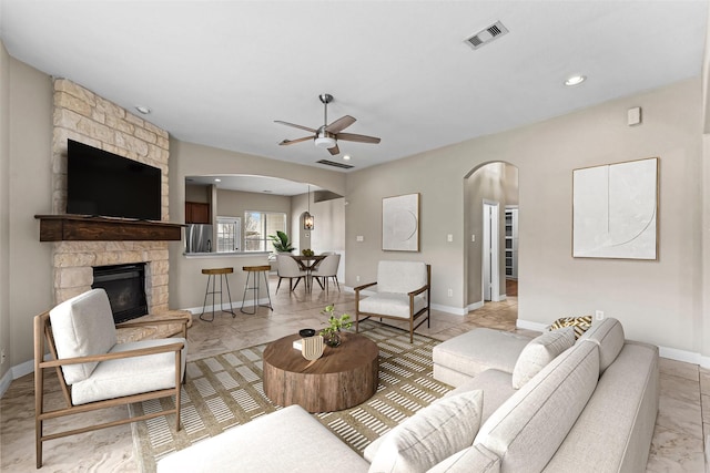 living room featuring visible vents, arched walkways, baseboards, and ceiling fan