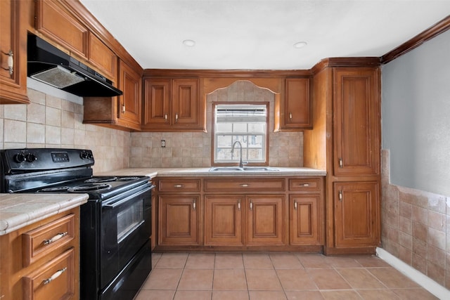 kitchen featuring a sink, under cabinet range hood, brown cabinets, and black electric range oven