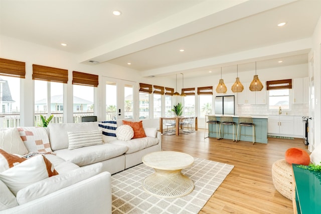 living area featuring recessed lighting, french doors, beamed ceiling, and light wood-style flooring