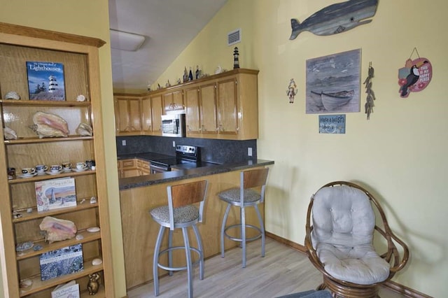 kitchen with brown cabinets, lofted ceiling, visible vents, light wood-style flooring, and appliances with stainless steel finishes