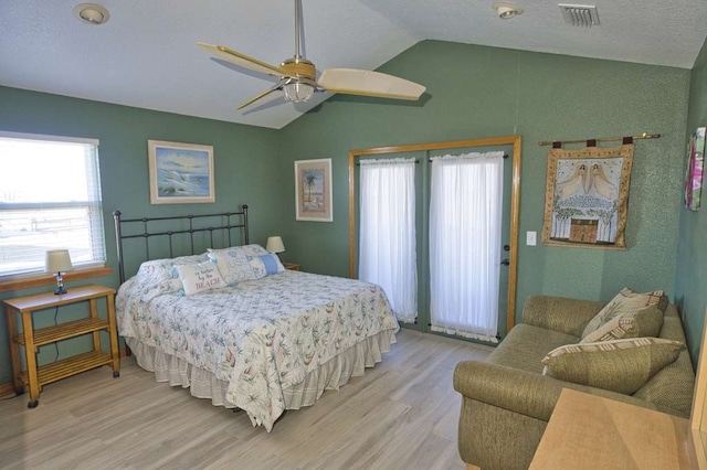 bedroom featuring a ceiling fan, visible vents, vaulted ceiling, and light wood-style flooring