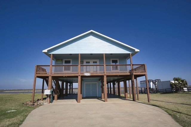 beach home featuring concrete driveway, stairs, a porch, a carport, and a front yard