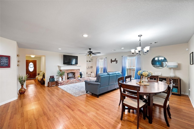 1009 Canadian St, Houston, TX 77009 - dining space featuring light wood-style flooring, a brick fireplace, ceiling fan with notable chandelier, and visible vents