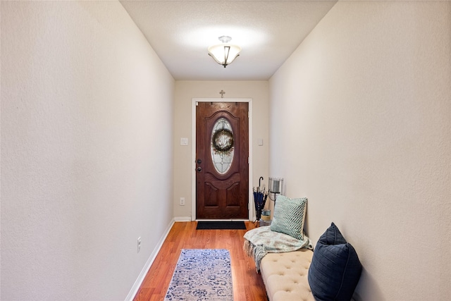 doorway to outside featuring baseboards and wood finished floors