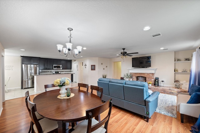 1009 Canadian St, Houston, TX 77009 - dining room featuring a fireplace, light wood-style flooring, ceiling fan with notable chandelier, visible vents, and recessed lighting