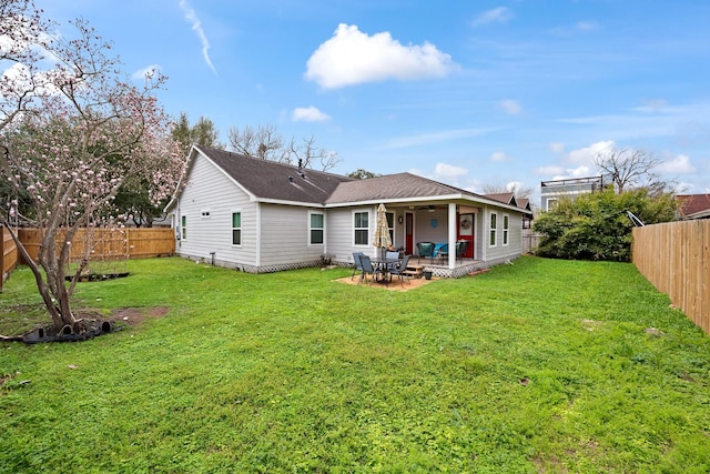 rear view of property featuring a yard, a fenced backyard, and a patio