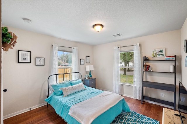 bedroom with baseboards, multiple windows, visible vents, and dark wood-type flooring