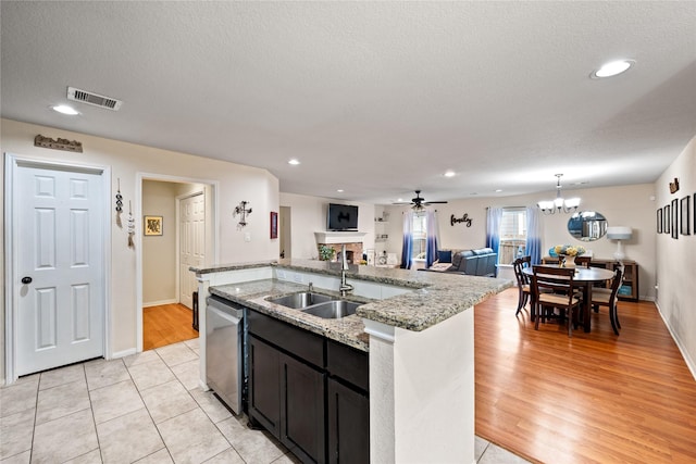 1009 Canadian St, Houston, TX 77009 - kitchen featuring a fireplace, a kitchen island with sink, a sink, open floor plan, and stainless steel dishwasher