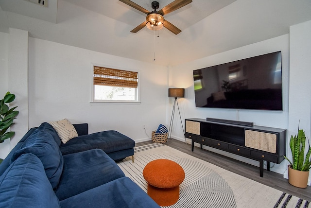 living area featuring dark wood-type flooring, a ceiling fan, and baseboards