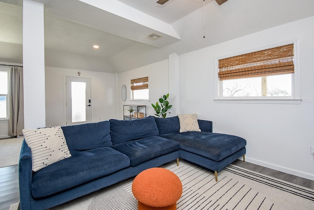 living area with lofted ceiling, a ceiling fan, visible vents, baseboards, and light wood finished floors