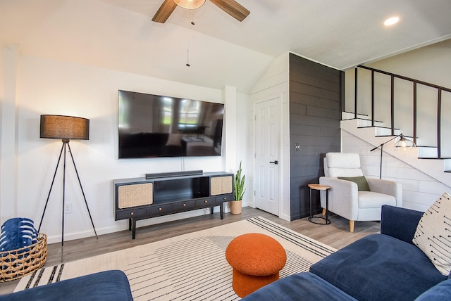 living room with lofted ceiling, a ceiling fan, wood finished floors, baseboards, and stairs