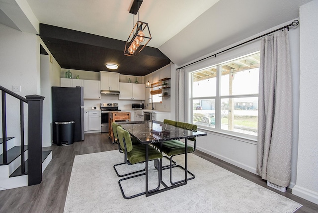 dining area with dark wood-style flooring, vaulted ceiling, baseboards, and stairs