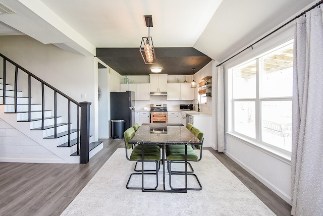 dining area with baseboards, visible vents, lofted ceiling, wood finished floors, and stairs