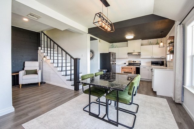 kitchen with freestanding refrigerator, hanging light fixtures, light countertops, under cabinet range hood, and white cabinetry