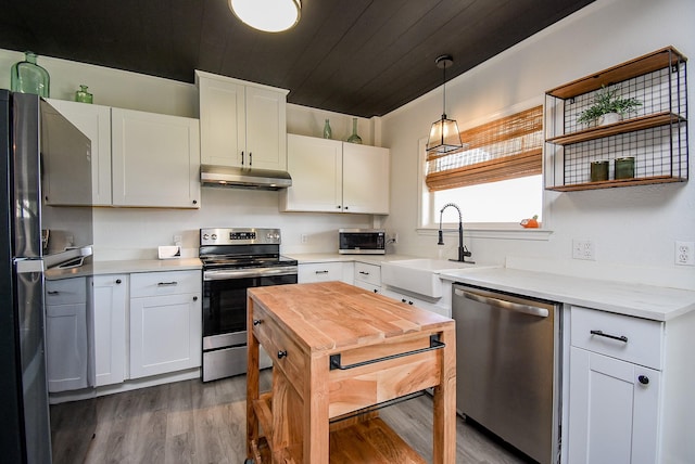 kitchen with pendant lighting, stainless steel appliances, white cabinetry, and under cabinet range hood