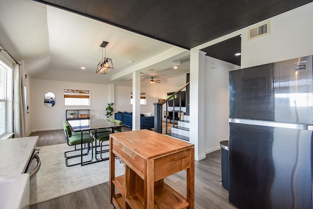 kitchen with visible vents, vaulted ceiling, light countertops, freestanding refrigerator, and dark wood finished floors