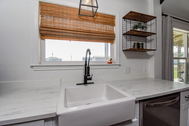 kitchen featuring a textured wall, a sink, light countertops, open shelves, and stainless steel dishwasher