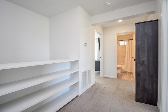 hall with visible vents and light colored carpet