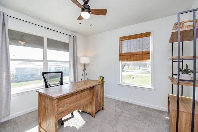 office space featuring baseboards, ceiling fan, and light colored carpet