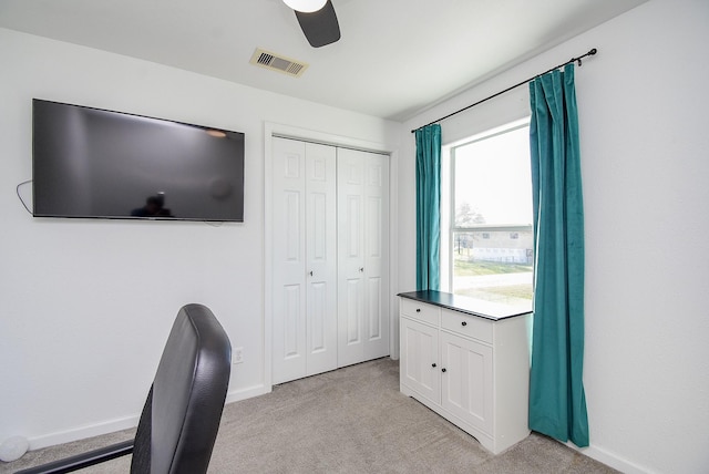 unfurnished office with baseboards, visible vents, a ceiling fan, and light colored carpet