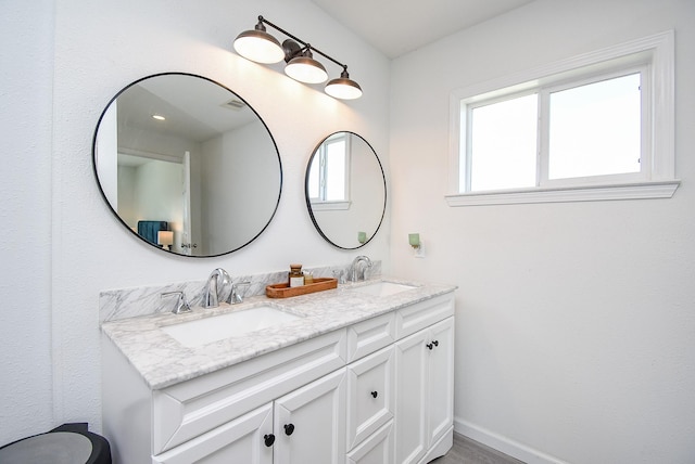 bathroom with visible vents, a sink, baseboards, and double vanity