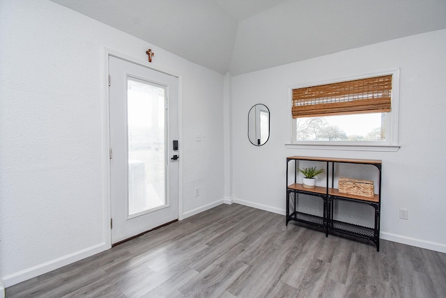 entryway with lofted ceiling, wood finished floors, and baseboards