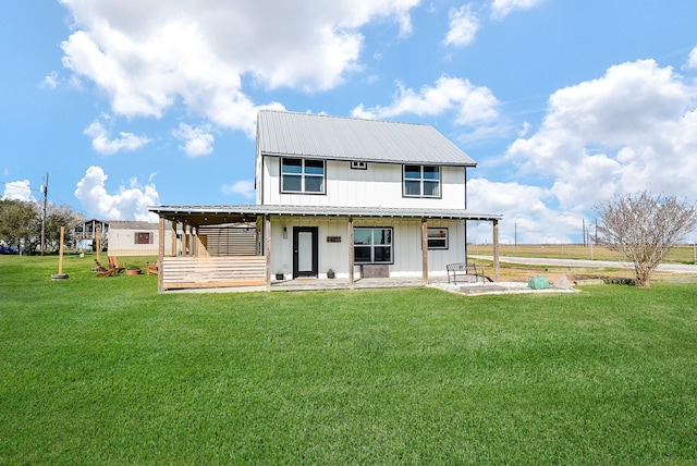 back of property with a yard, a patio area, metal roof, and board and batten siding