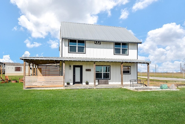 rear view of house featuring a lawn, metal roof, board and batten siding, and a patio