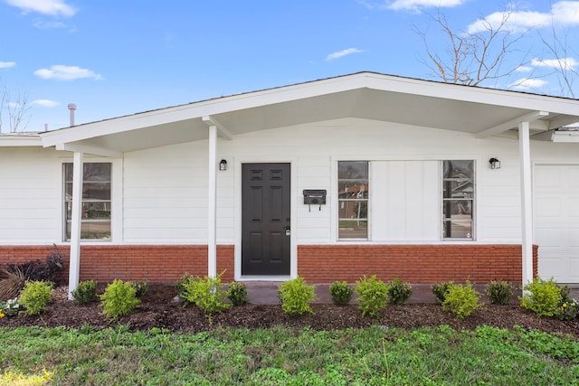 doorway to property featuring a garage and brick siding