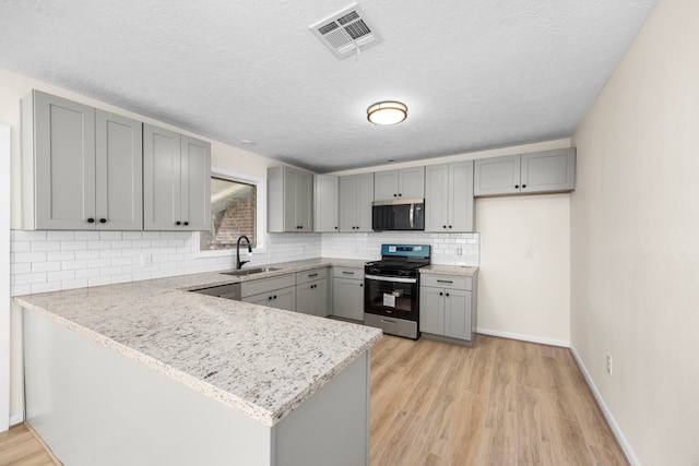 kitchen with visible vents, stainless steel appliances, a sink, and gray cabinetry