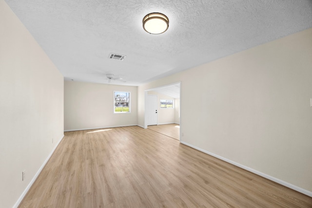 unfurnished room featuring light wood-type flooring, baseboards, visible vents, and a textured ceiling