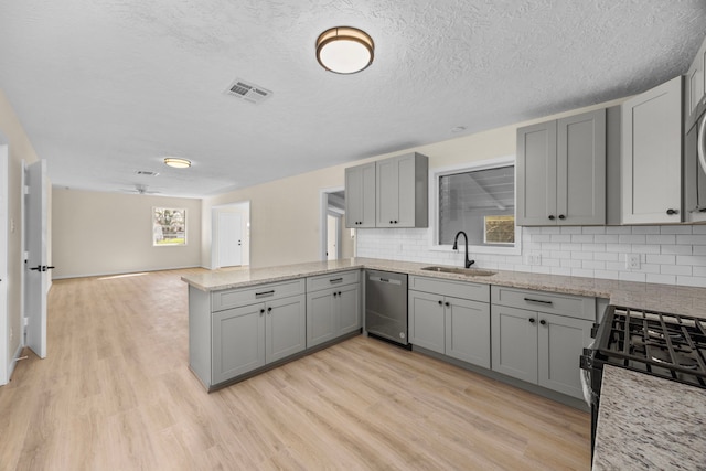 kitchen featuring gray cabinets, visible vents, a sink, dishwasher, and a peninsula