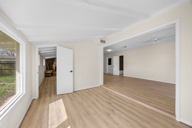 unfurnished room featuring ceiling fan, visible vents, baseboards, light wood-style floors, and beam ceiling