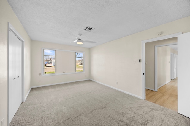 spare room featuring visible vents, light carpet, ceiling fan, a textured ceiling, and baseboards