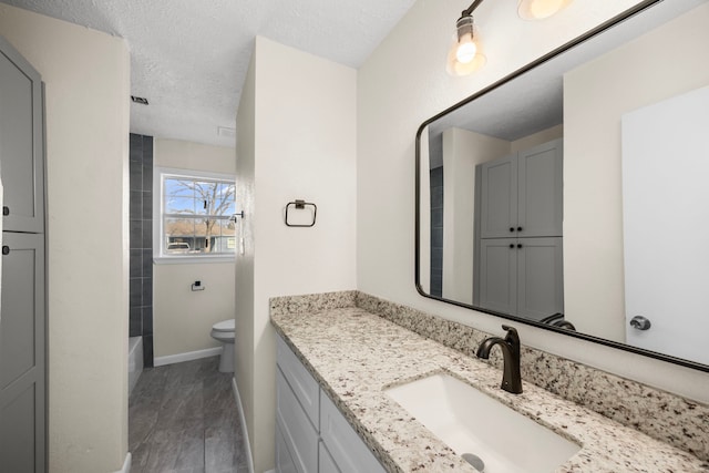 bathroom featuring baseboards, vanity, toilet, and a textured ceiling