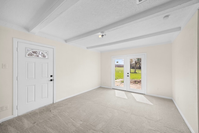 empty room with light carpet, a textured ceiling, beam ceiling, and french doors