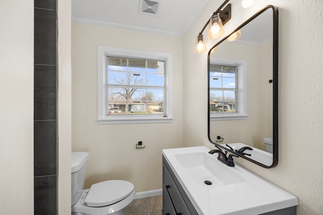 bathroom with visible vents, toilet, ornamental molding, vanity, and baseboards