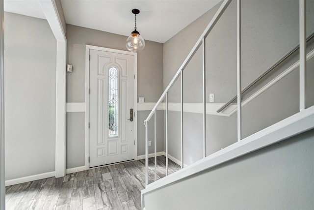 entrance foyer with stairway, wood finished floors, and baseboards