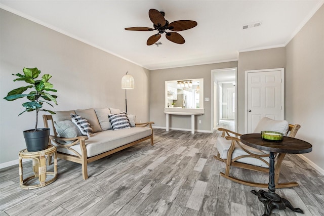 living room featuring visible vents, crown molding, baseboards, and wood finished floors