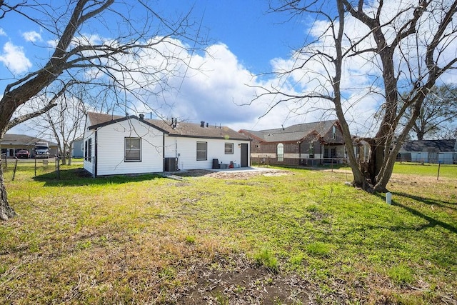 rear view of property featuring central air condition unit, fence, and a yard