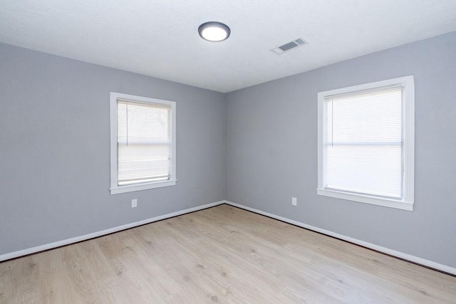 unfurnished room featuring light wood-type flooring, baseboards, and visible vents