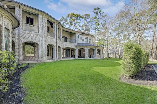 rear view of house featuring a balcony, a lawn, and brick siding