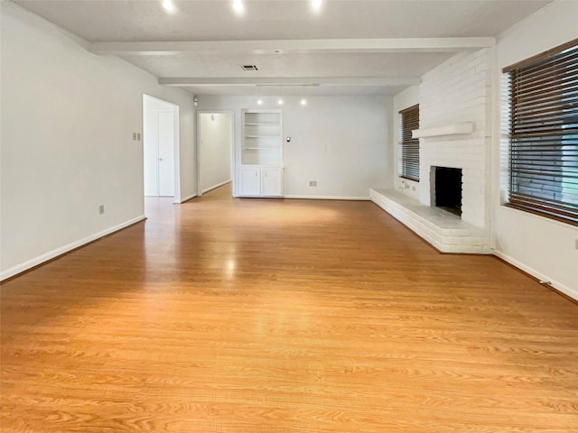 unfurnished living room with light wood finished floors, a fireplace, baseboards, and beamed ceiling