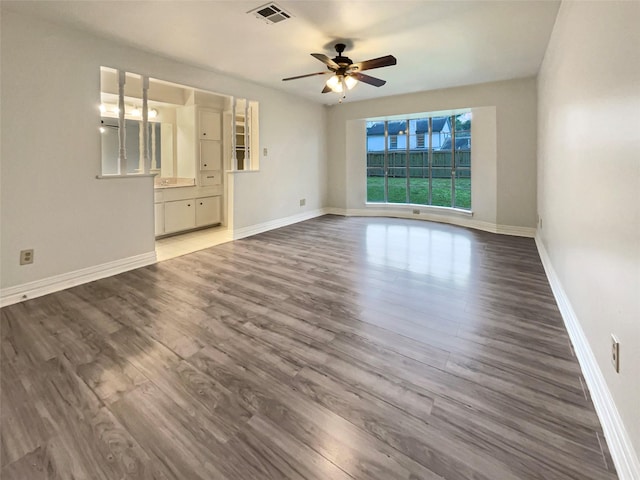 unfurnished room featuring a ceiling fan, visible vents, baseboards, and wood finished floors