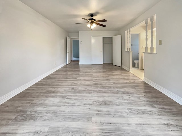 unfurnished bedroom with light wood-type flooring, a closet, connected bathroom, and baseboards