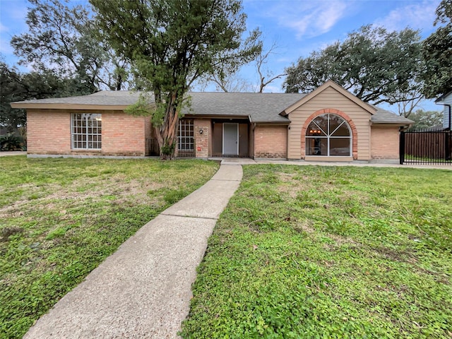 ranch-style home featuring a shingled roof, brick siding, fence, and a front lawn