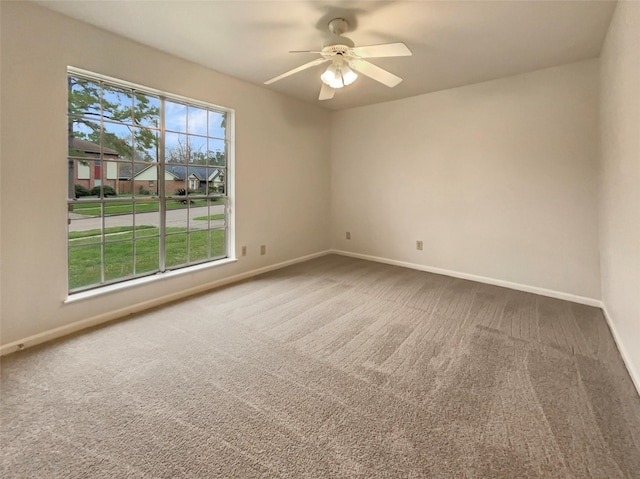 carpeted empty room featuring baseboards and a ceiling fan