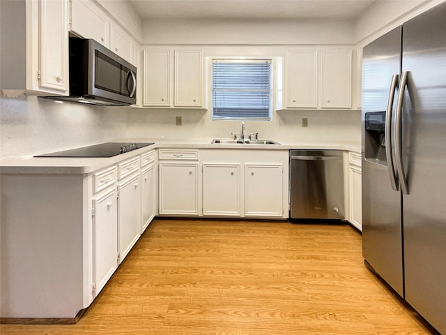 kitchen with appliances with stainless steel finishes, light countertops, light wood-style floors, white cabinetry, and a sink